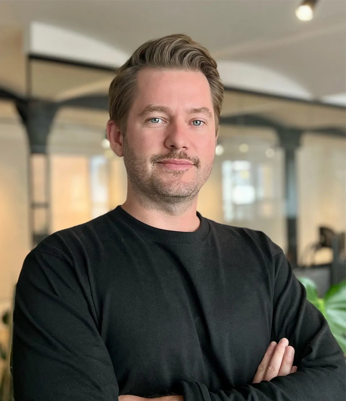 Portrait von Co-CEO Chris in schwarzem Pullover in modernem Büro.